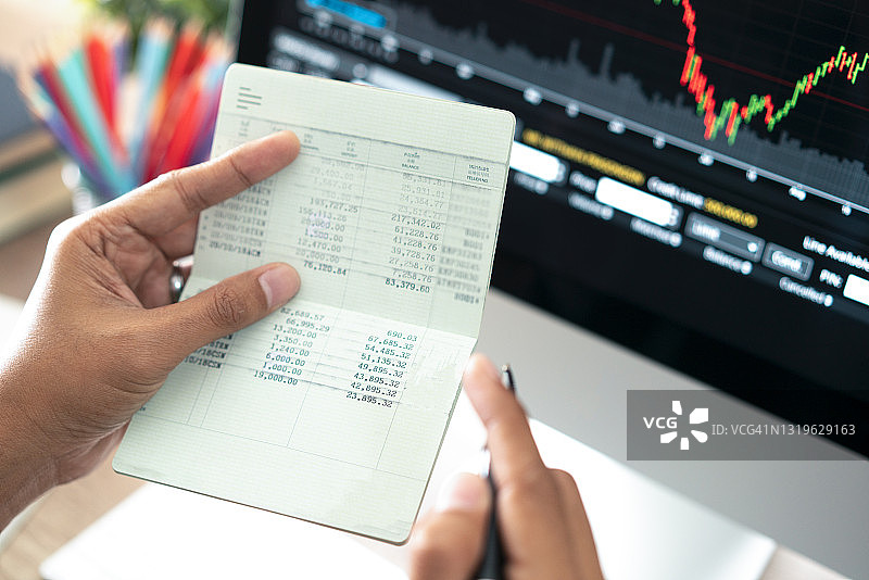 手持存折、银行账本和笔记本电脑图片素材