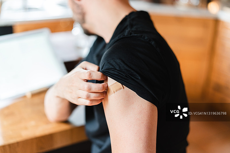 男人接种新冠疫苗后挠胳膊图片素材