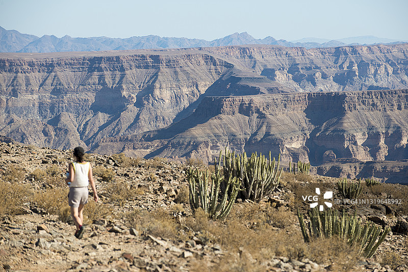 一名女子在纳米比亚的鱼河峡谷边缘行走图片素材