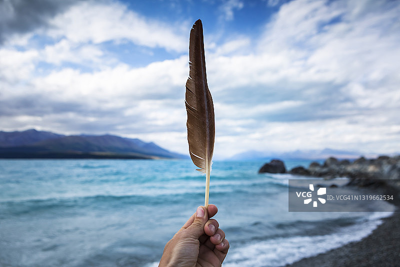 新西兰坎特伯雷：手持羽毛，背景是蒂卡普湖图片素材