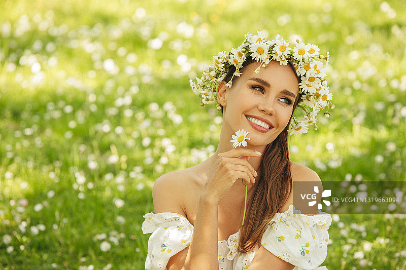 微笑的年轻女子坐在草地上图片素材