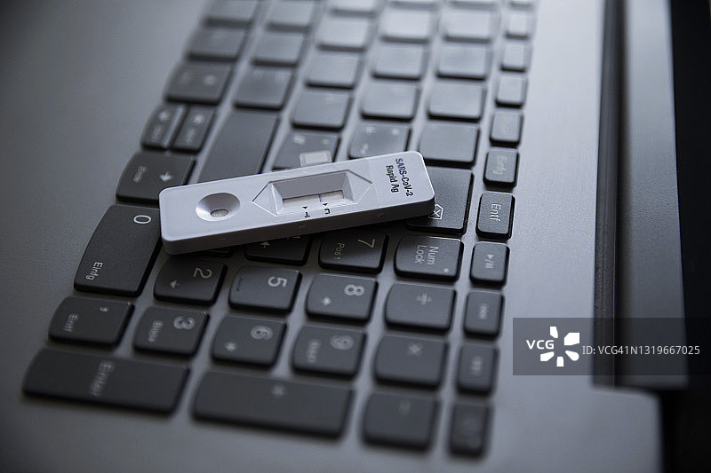 家中笔记本电脑上的新冠快速检测试剂盒图片素材