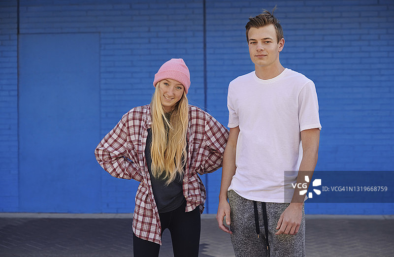 年轻情侣站在蓝色墙壁前图片素材