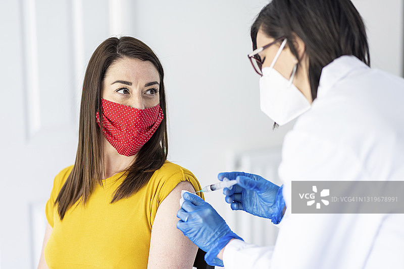 疫情期间，女医生在诊所为女子接种新冠疫苗图片素材