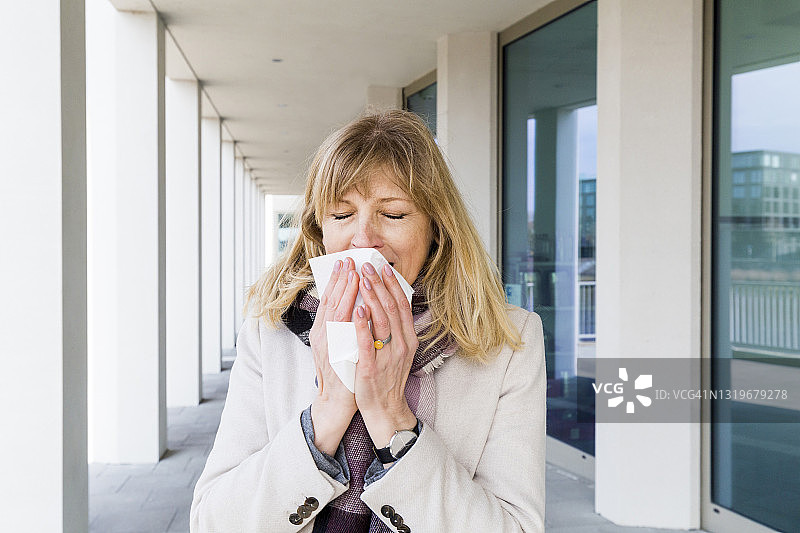 站在走廊里打喷嚏的中年妇女图片素材