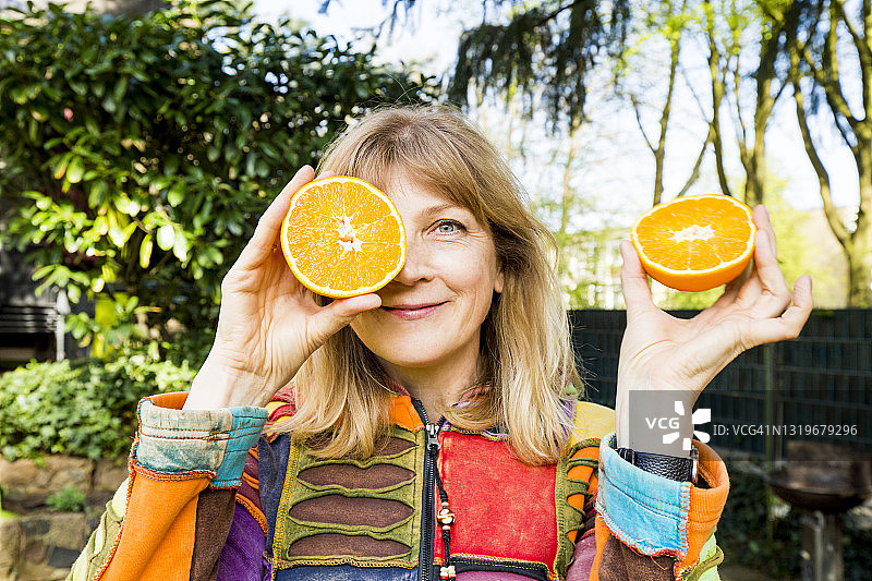 中年妇女在户外用半个橙子敷眼图片素材
