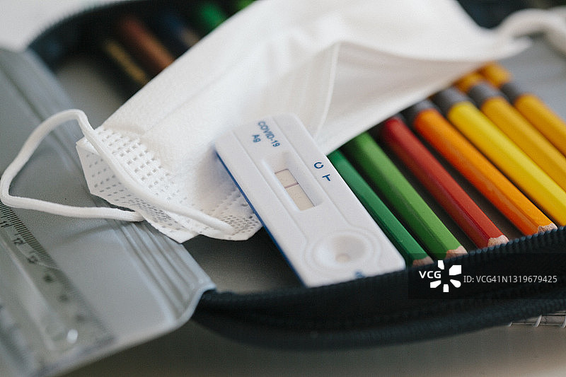 学校铅笔盒中的快速诊断试剂盒和防护口罩图片素材