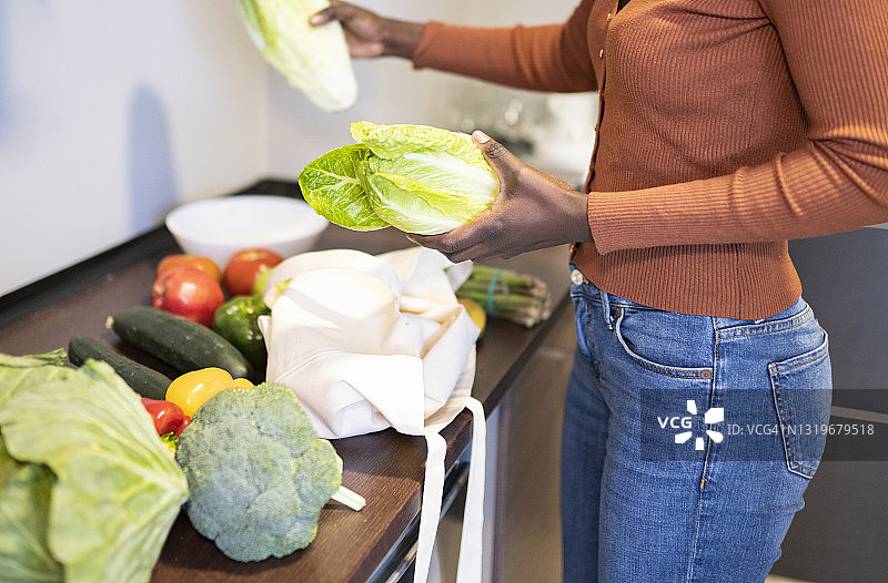 中年妇女在家中检查厨房台面上的食品杂货图片素材