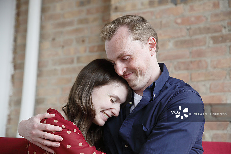 白人千禧一代情侣在阁楼空间里亲切地拥抱，身着休闲服装图片素材