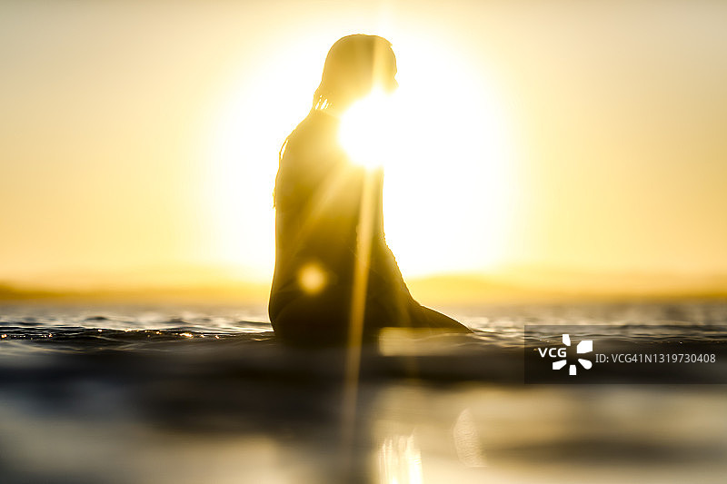 在日落时分站在冲浪板上的女人图片素材