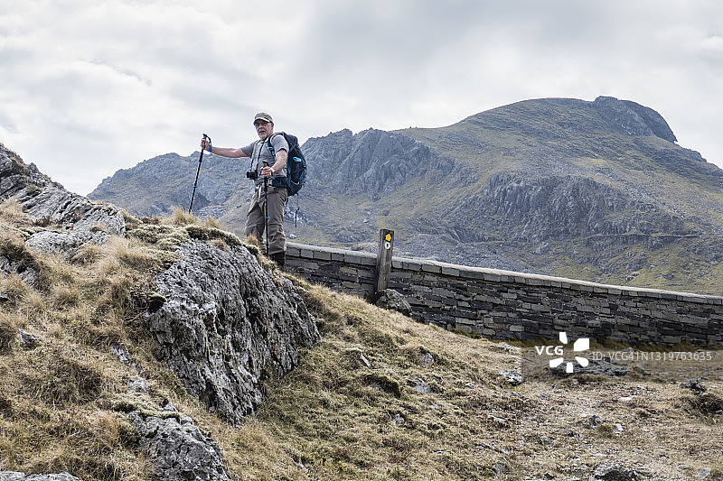 年长的白人男子背着背包戴着帽子看着镜头图片素材