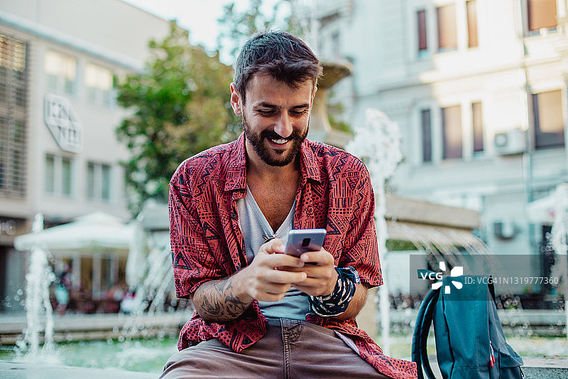 有纹身的年轻男人在使用手机图片素材