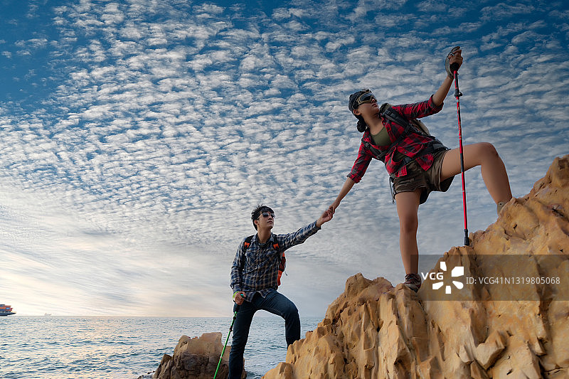 一对徒步旅行者攀登悬崖，互助合作图片素材