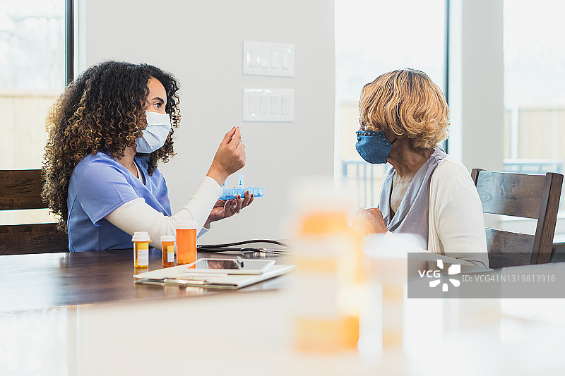 女护士教病人如何使用药盒整理器图片素材