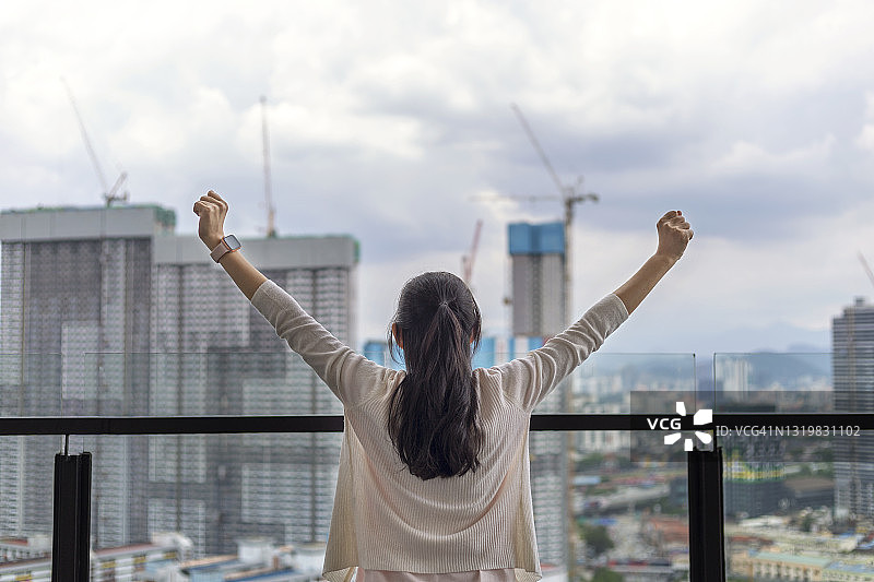 在阳台上伸展双臂的女人图片素材
