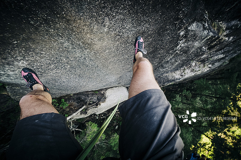 在高空绳降时，攀岩者从岩壁上弹跳下来的主观镜头图片素材