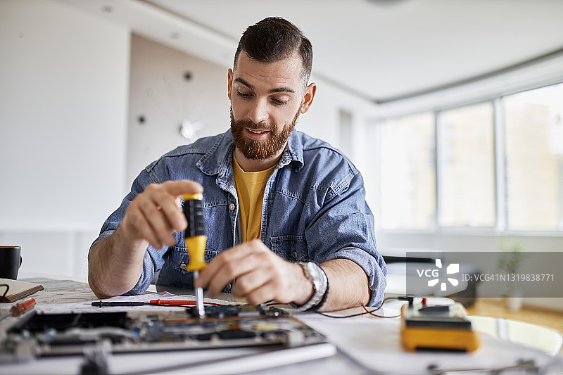 在车间里工作的男人，工作台上摆满了修理电路所需的各种工具和物品图片素材