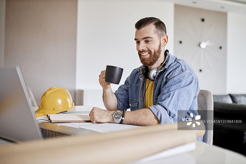 男子在家用笔记本电脑工作并喝咖啡图片素材