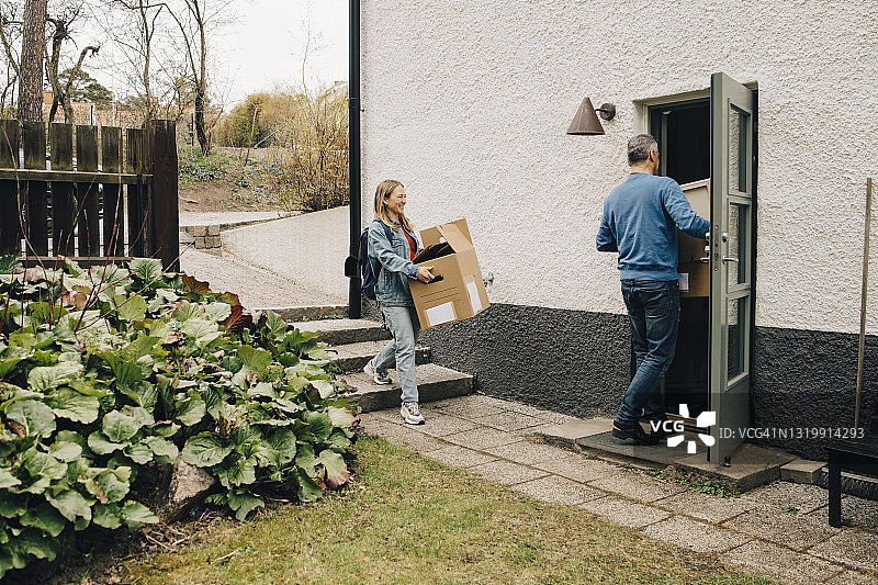微笑的年轻女人和父亲在后院搬运箱子图片素材