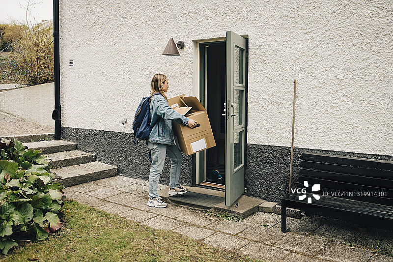 年轻女子在后院门口搬运箱子图片素材