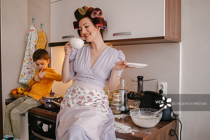 妈妈和儿子一起做饭，休息时喝咖啡图片素材