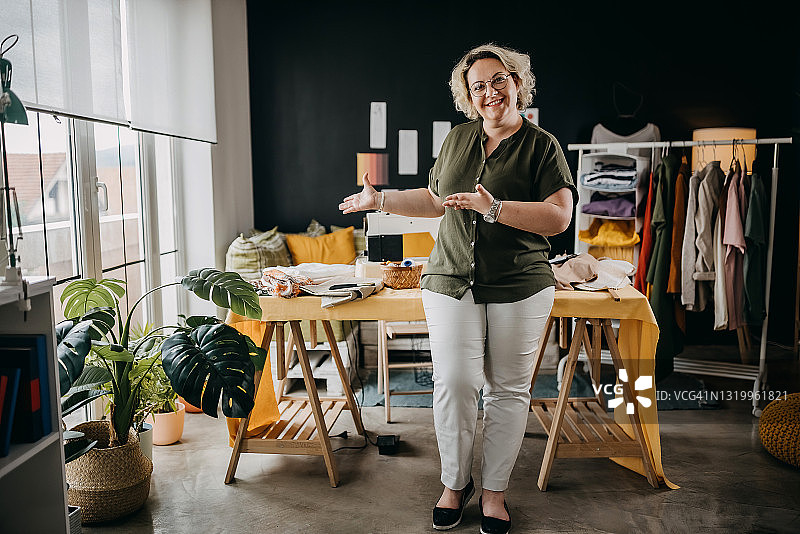 快乐微笑的创意时装设计师在自己的服装店工作图片素材