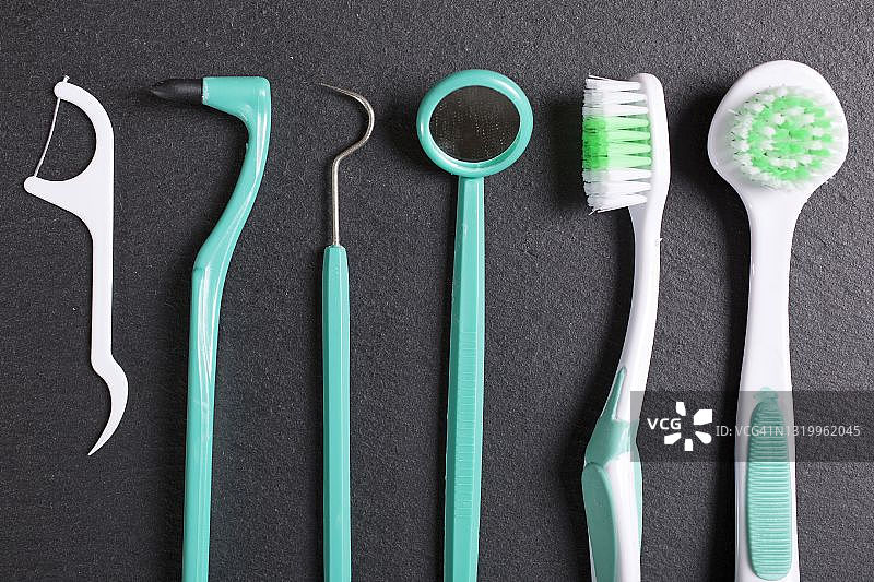 黑色石板上的牙科刷子和工具精选图片素材