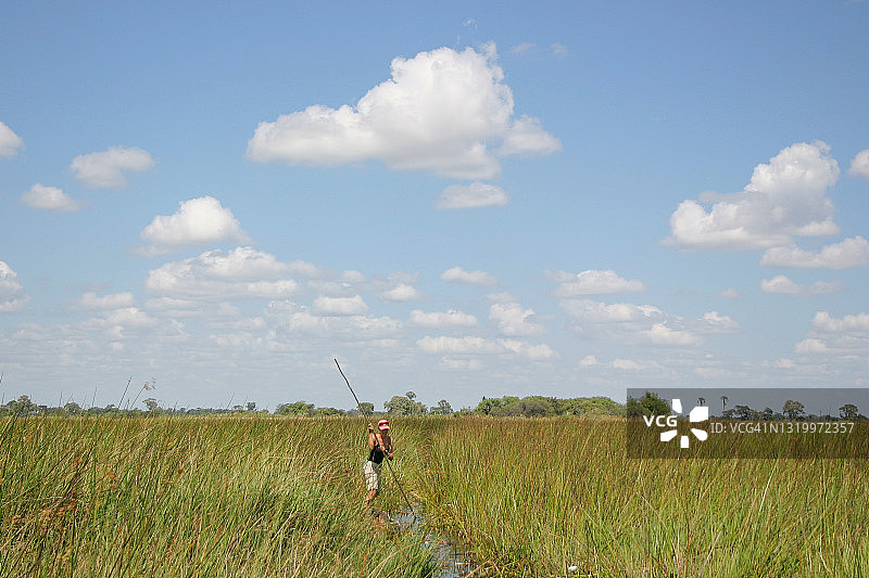 在博茨瓦纳奥卡万戈三角洲乘坐独木舟的游客图片素材