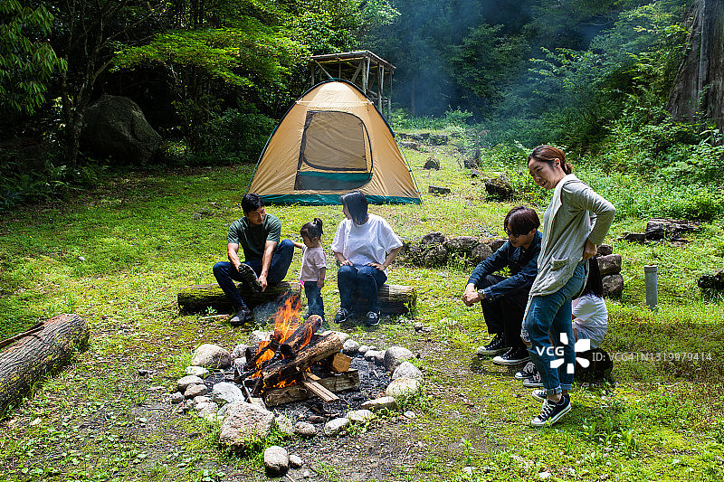年轻的朋友和家人围坐在野外的营火旁图片素材