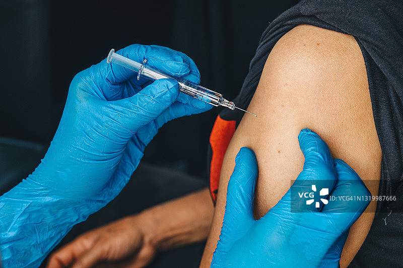 医生或护士为患者接种新冠疫苗的肩部特写图片素材