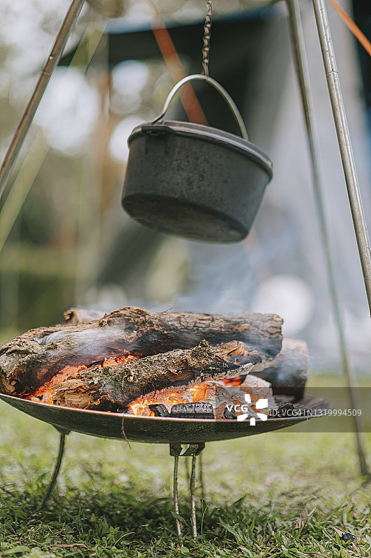 露营之旅中的傍晚篝火，家人忙着在燃烧的柴火背景上准备晚餐图片素材