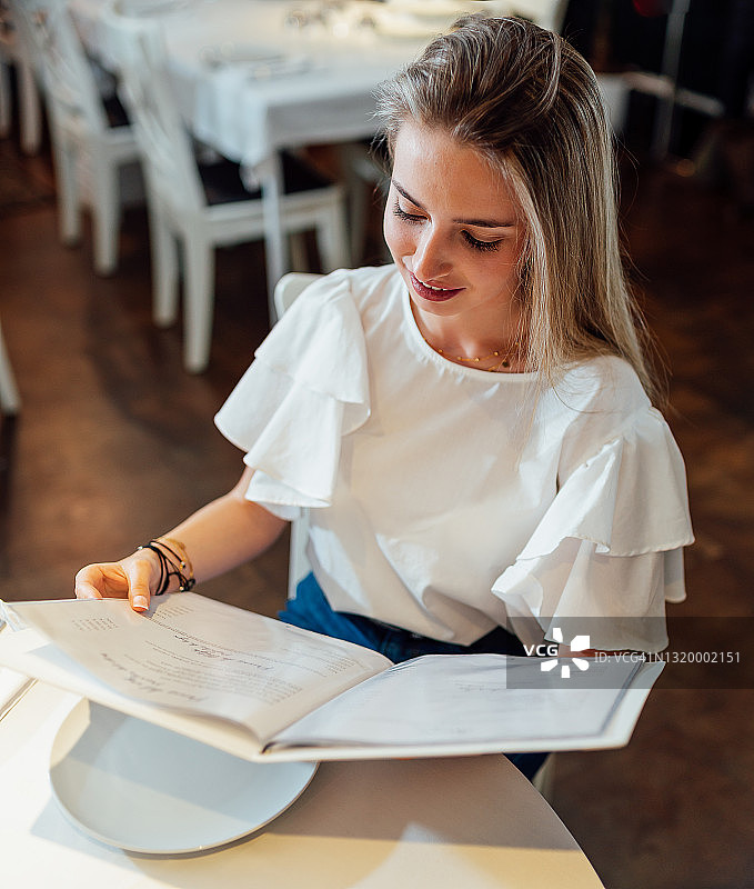年轻女人在高级餐厅阅读菜单图片素材
