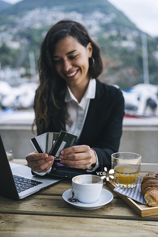 年轻女商人在户外咖啡馆使用信用卡图片素材