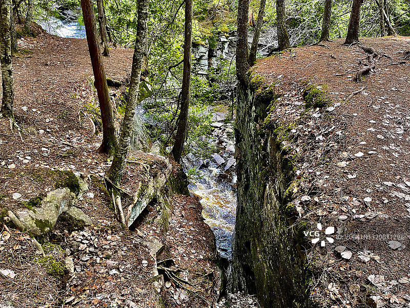 沿着崎岖小径徒步旅行，欣赏峡谷瀑布的岩层和美丽的河流景观图片素材