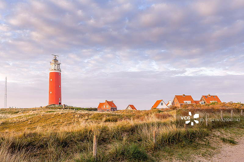 特塞尔岛上沐浴在傍晚光辉中的红色灯塔图片素材