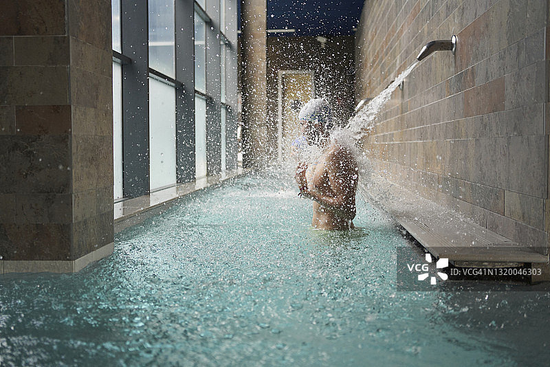 男子在水疗中心瀑布下享受水按摩侧视图图片素材