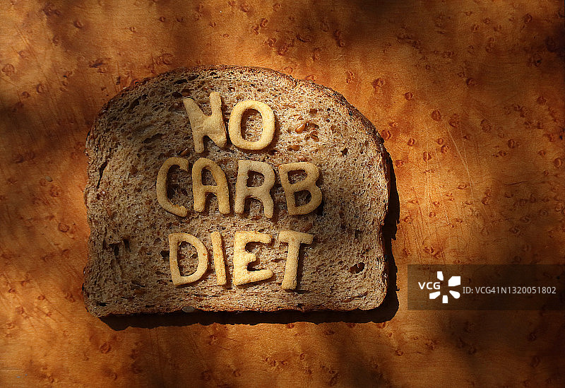 一片小麦面包，上面用烘焙面团字母拼出“NO CARB DIET”字样图片素材