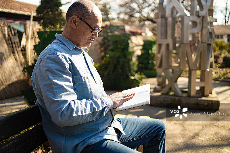 男人坐在长椅上阅读科学文献图片素材