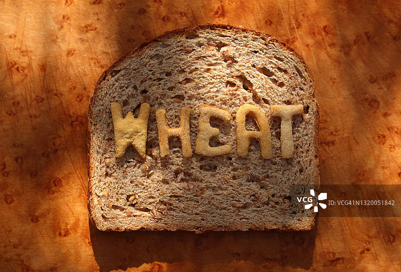 小麦面包切片，上面有用烘焙面团字母制成的“小麦”字样——系列的一部分图片素材
