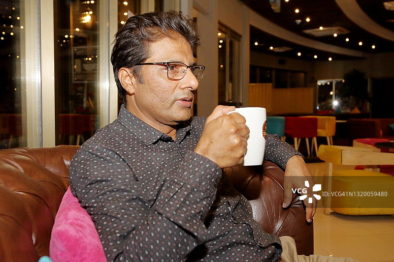 中年男人拿着咖啡杯的侧面照图片素材