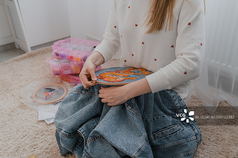 在家在地板上刺绣牛仔夹克的女人图片素材