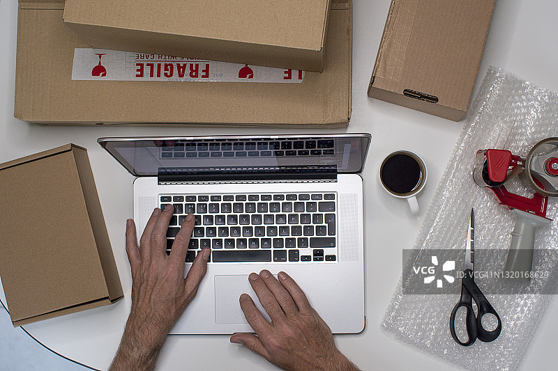 手与笔记本电脑、包裹和包装材料的俯视图图片素材