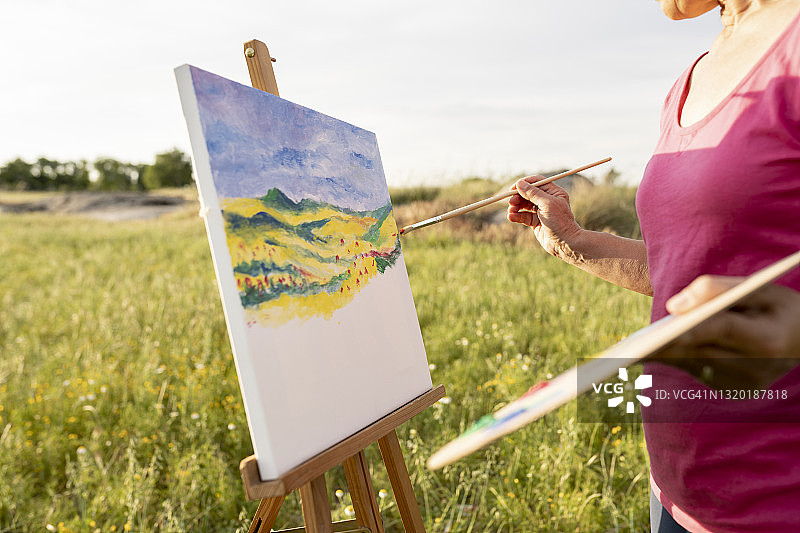 女人在自然环境中手持画笔和调色板粉刷房间图片素材