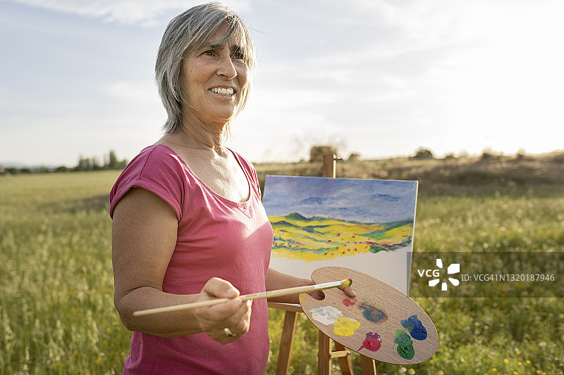 快乐的妇女在野外画画图片素材