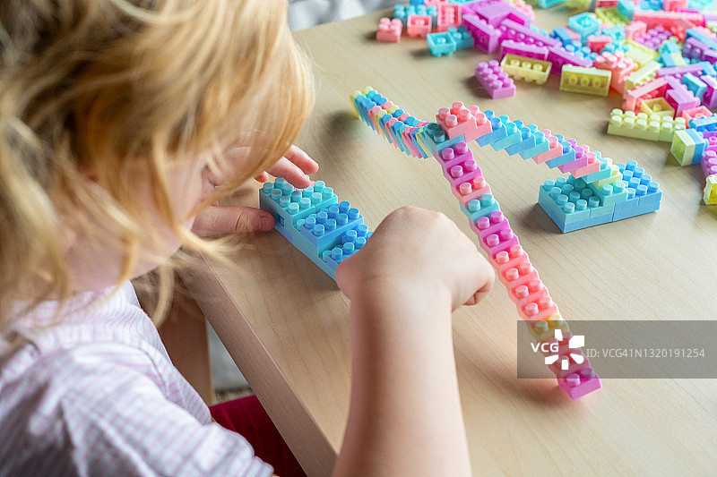 小女孩在桌边玩彩色积木图片素材