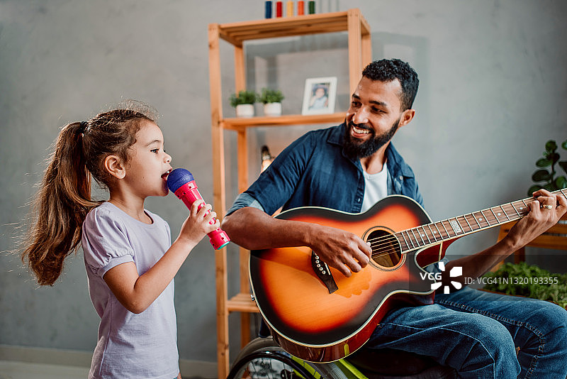 坐在轮椅上的父亲和女儿快乐地唱歌图片素材