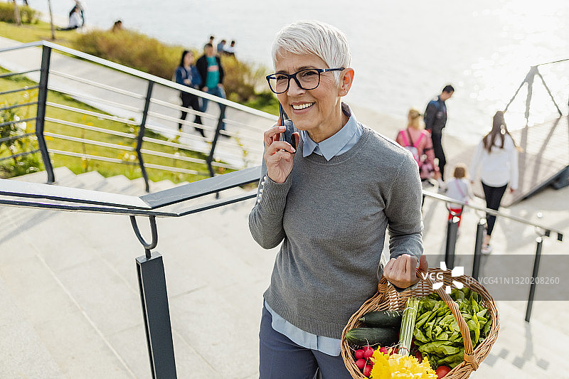 年长的女人一边打电话一边走路图片素材