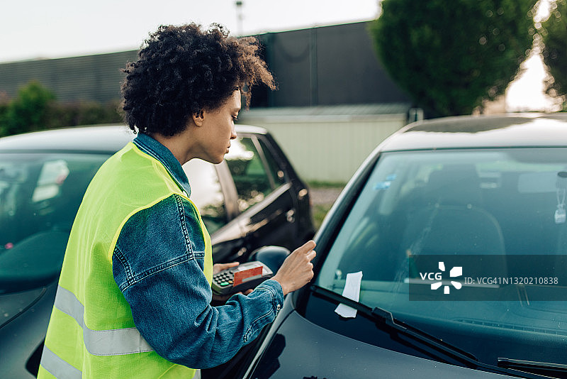 停车管理员在违规停放的车辆上放置罚款单图片素材