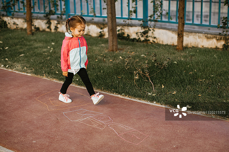 活泼的小女孩快乐地玩跳房子游戏图片素材