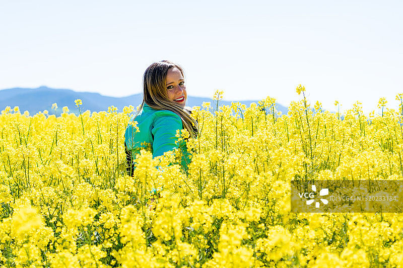 在油菜花田中看向镜头的金发女子图片素材